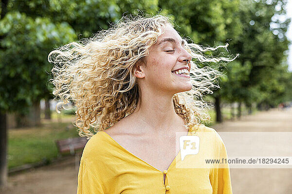 Glückliche junge Frau mit blonden Haaren genießt den Park