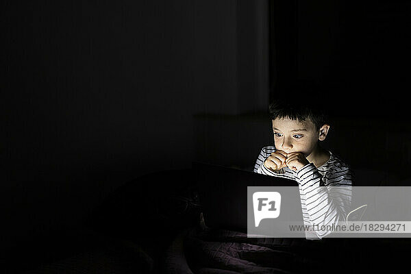 Boy watching scary movie on laptop at home