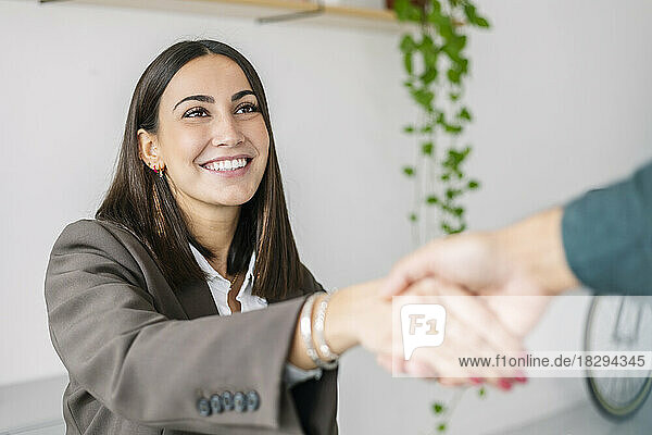 Happy recruiter shaking hand with candidate in office
