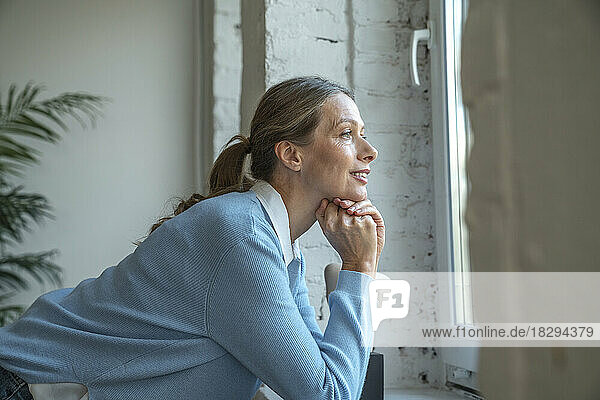 Thoughtful businesswoman looking through window in office