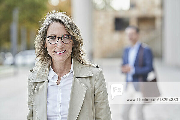 Smiling mature businesswoman wearing eyeglasses standing on footpath