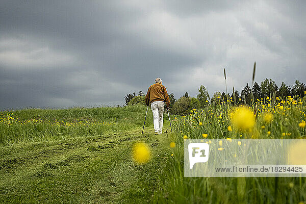 Älterer Mann läuft auf einem Feldweg unter dem Himmel