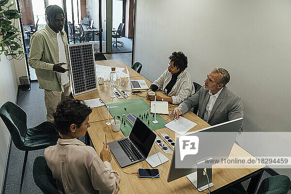 Young businessman discussing with colleagues over solar panel