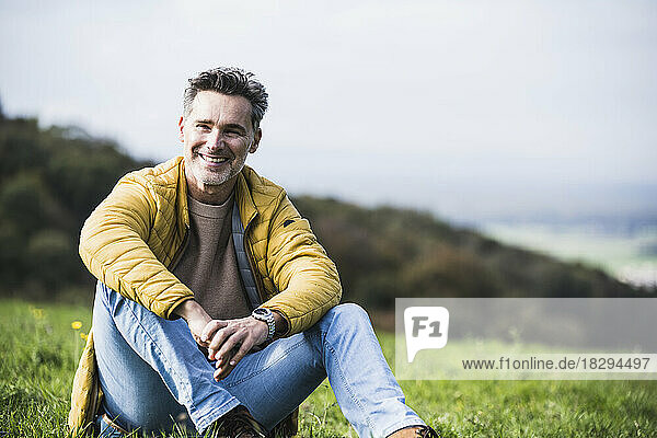 Happy mature man sitting on grass