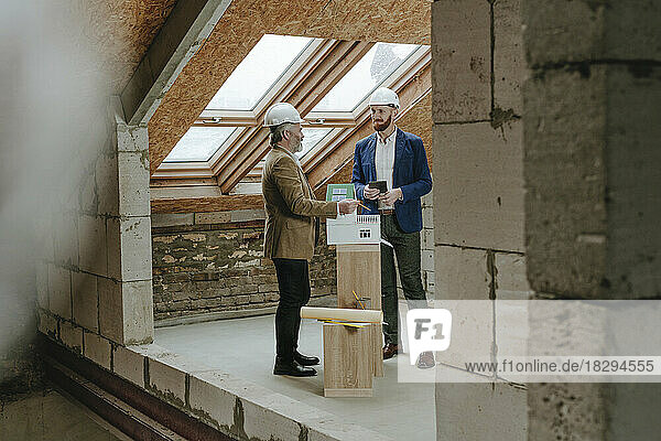 Architects discussing by house model at construction site