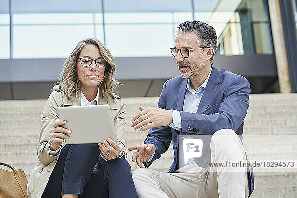 Reife Geschäftsleute diskutieren mit Tablet-PC über Schritte