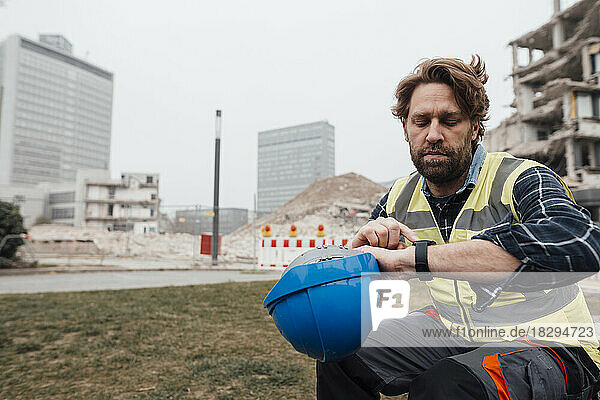 Mature worker checking time on watch at construction site