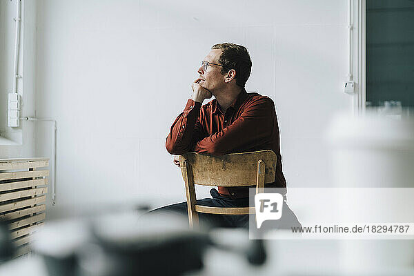 Thoughtful businessman with hand on chin sitting on chair