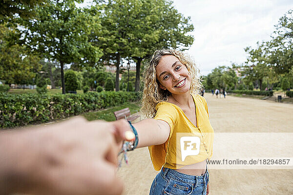Lächelnde Frau hält die Hand eines Freundes im Park