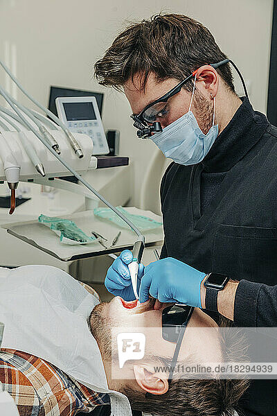 Dentist examining patient's teeth with equipment in clinic