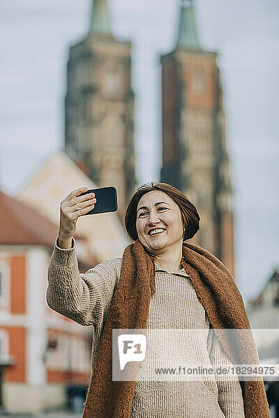Happy mature woman taking selfie through smart phone