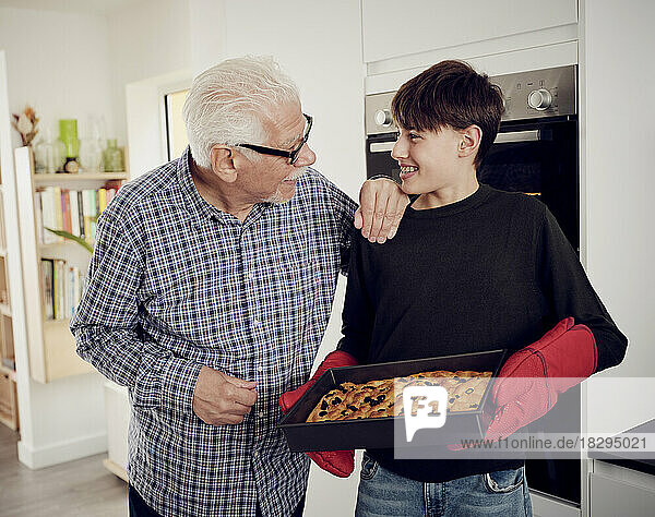 Großvater und Enkel halten Backblech mit frischem Focaccia-Brot in der Küche