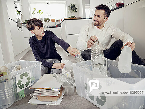 Father and son separating waste into recycling boxes