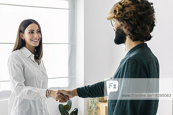 Happy businesswoman shaking hand with businessman in office