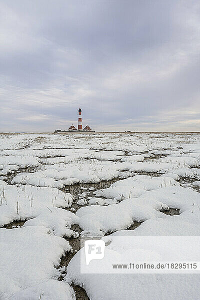 Germany  Schleswig-Holstein  Westerhever  Snow-covered landscape at dusk with Westerheversand Lighthouse in background
