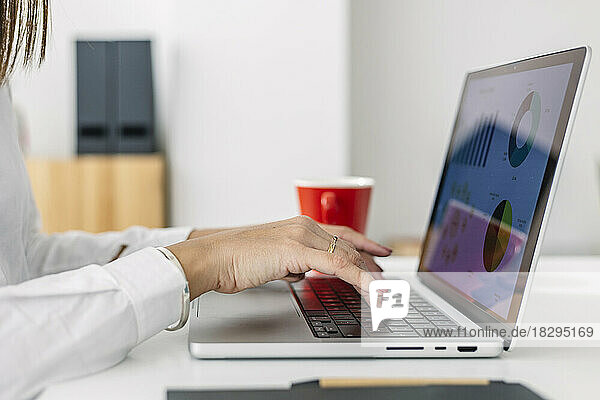 Hands of businesswoman using laptop at desk