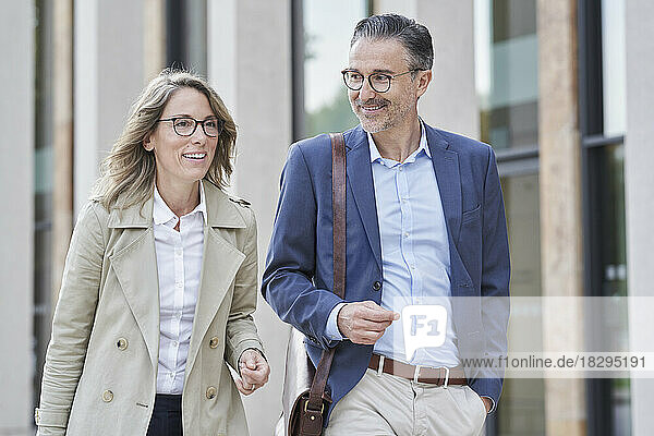 Happy mature business people walking together outside building