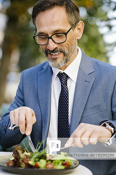 Happy mature businessman having lunch at cafe
