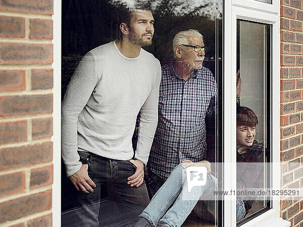 Großvater  Vater und Sohn schauen zu Hause aus dem Fenster