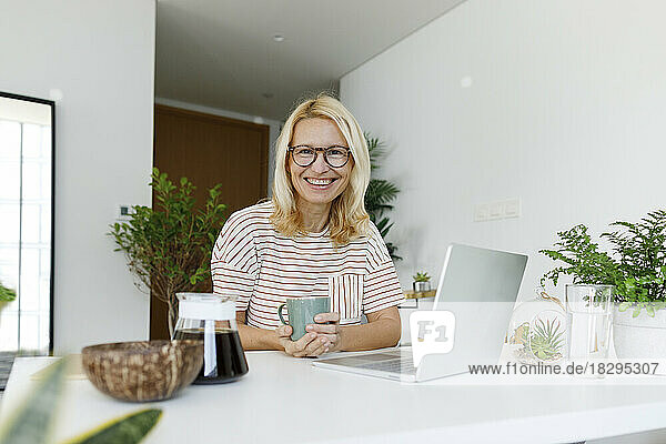 Happy freelancer wearing eyeglasses sitting at desk