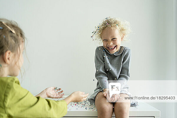 Süße Mädchen spielen zu Hause mit Konfetti