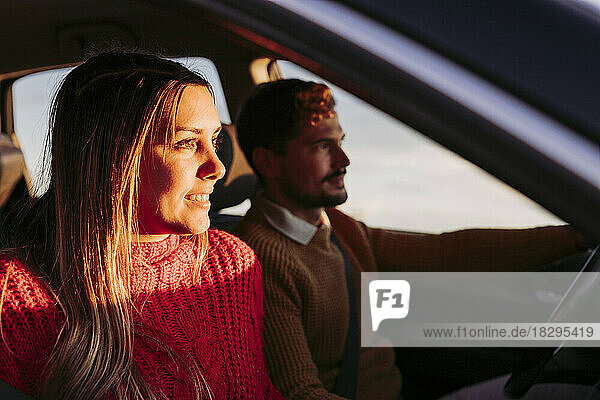 Paar fährt im Auto und Frau schaut ins Sonnenlicht