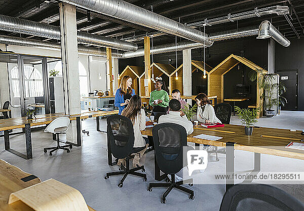 Businesswoman having discussion with colleagues in coworking office