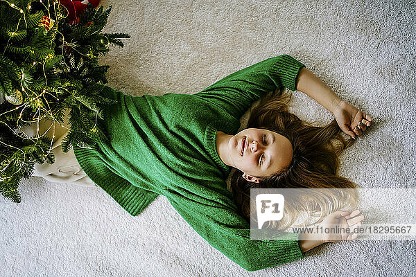 Girl with eyes closed lying on carpet at home