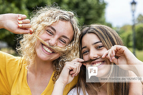 Happy friends with hair mustache in park