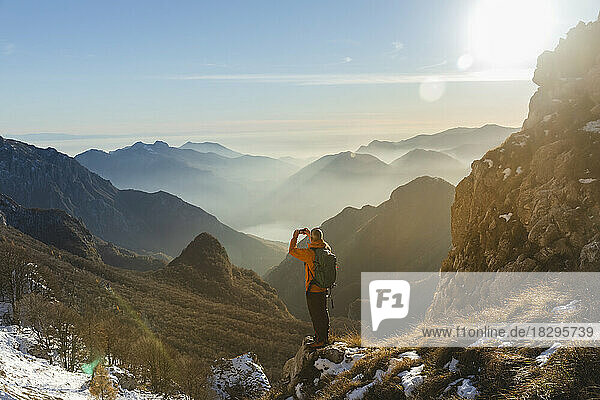 Hiker photographing through smart phone standing on mountain