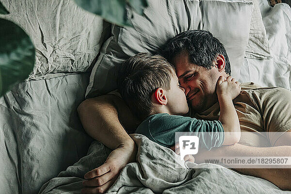 Smiling man with boy sleeping in bed