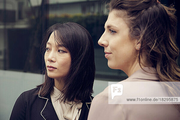 Contemplative businesswoman with colleague in front of building