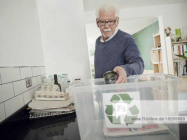 Senior man putting separated waste into recycling box