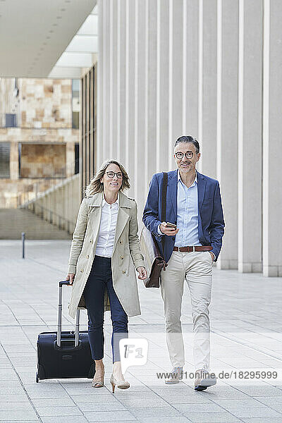 Businesswoman and colleague walking with colleague on footpath