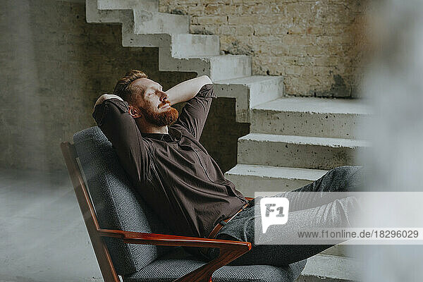 Happy businessman resting in chair at under construction site