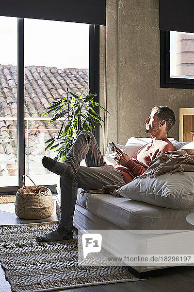 Man with smart phone sitting on sofa at home