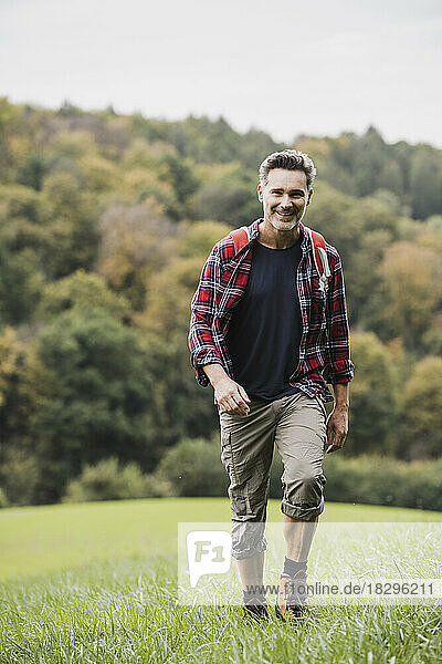 Happy mature man walking on grass in meadow