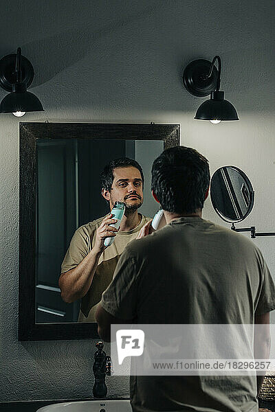 Man shaving with electric razor in bathroom