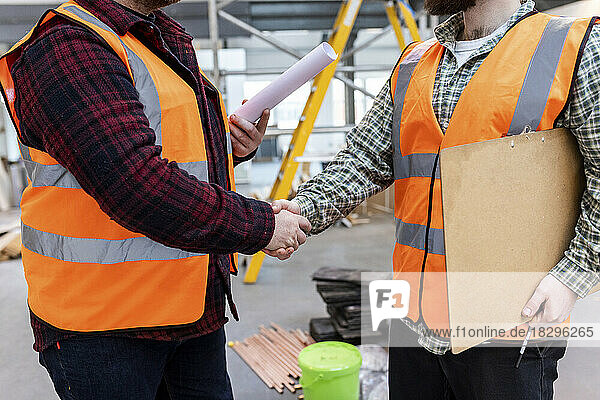 Engineers shaking hands with each other at construction site