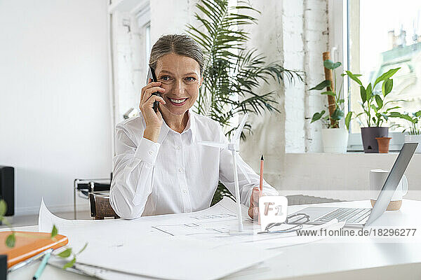 Smiling mature businesswoman talking over smart phone in office
