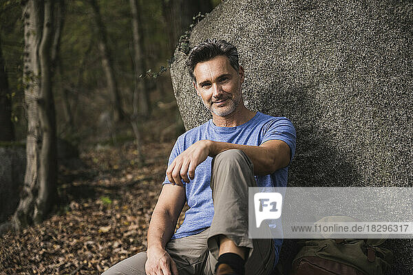 Smiling mature man sitting by rock