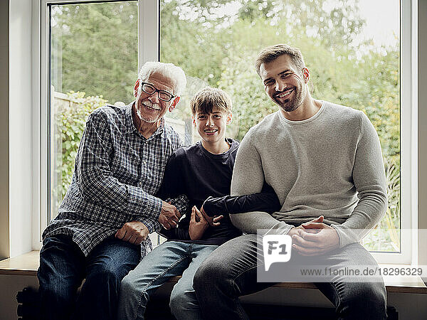 Glücklicher Großvater  Vater und Sohn sitzen zu Hause am Fenster