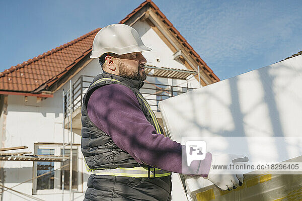 Bauarbeiter hält an sonnigem Tag Polystyrolschaum in der Hand