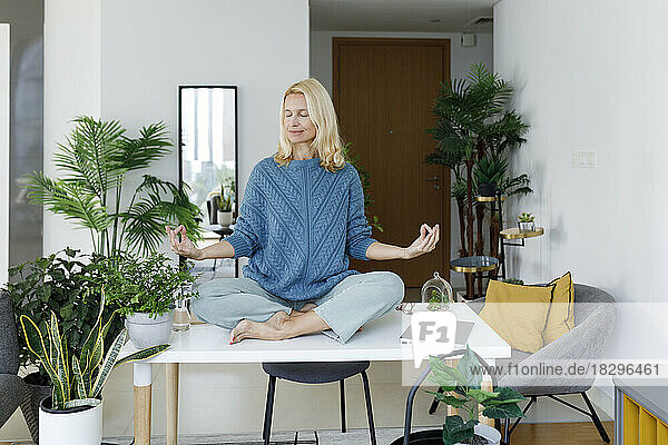 Smiling woman meditating on desk at home