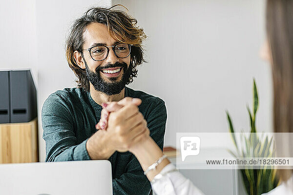 Smiling businessman holding colleague's hand in office