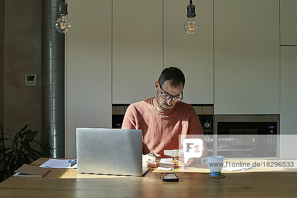 Man examining and calculating financial bills on desk at home