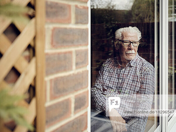Nachdenklicher älterer Mann schaut zu Hause aus dem Fenster