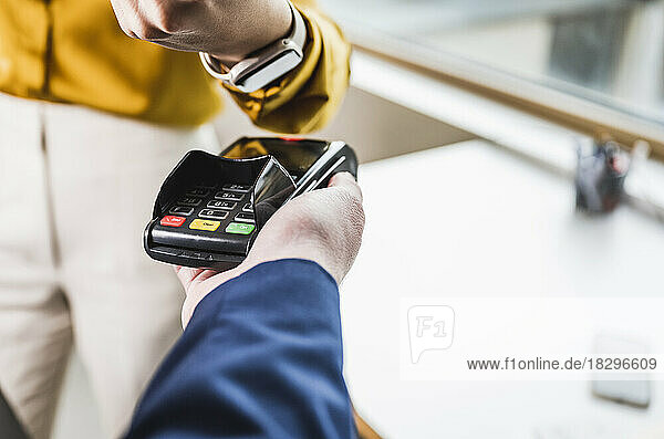Businesswoman paying with smart watch on card reader machine