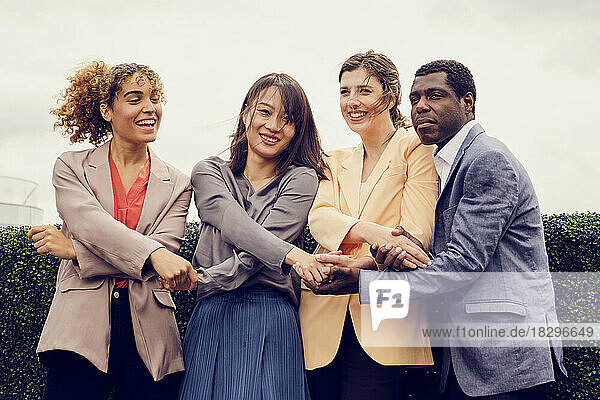 Happy businesswoman with colleagues congratulating each other on rooftop