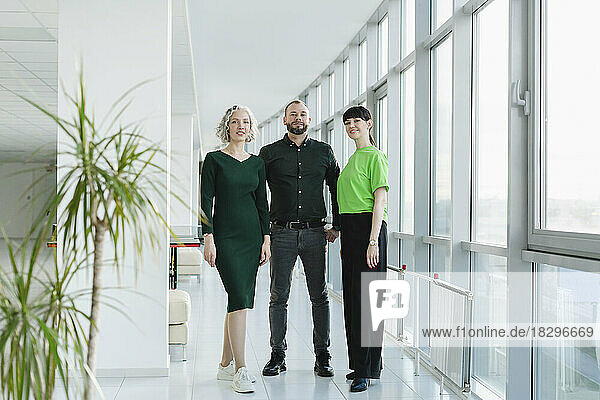 Three business people in green clothing standing on office floor
